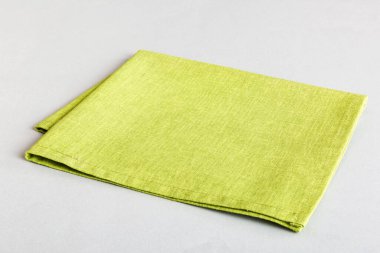 top view with green kitchen napkin isolated on table background. Folded cloth for mockup with copy space, Flat lay. Minimal style.