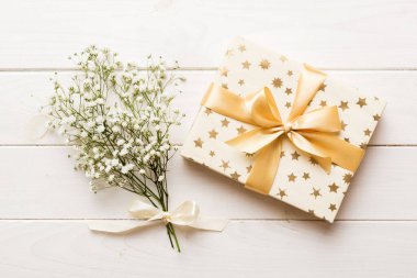 Hediye kutusu ya da hediye kutusu ve çiçek çıngıraklı yılanı ışık masasının üstünde. Tebrik kartı. Kopya alanı ile düz uzanma biçimi.