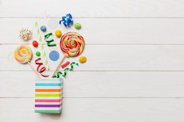 gift box in corner full of assorted traditional candies falling out on colored background with copy space. Happy Holidays sale concept.