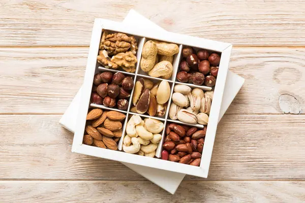 Stock image Various varieties of nuts lying in paper box on table background. Top view. Healthy food. Close up, copy space, top view, flat lay. Walnut, pistachios, almonds, hazelnuts and cashews.