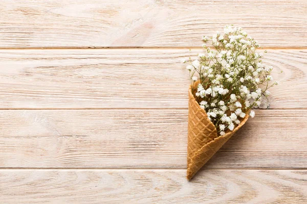 Waffle cone with beautiful gypsophila flowers on color background. summer concept. Copy space top view.