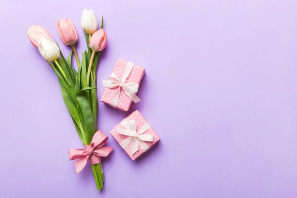 stock image Pink tulips flowers and gift or present box on colored table background. Mothers Day, Birthday, Womens Day, celebration concept. Space for text top view.