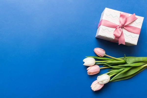 stock image Pink tulips flowers and gift or present box on colored table background. Mothers Day, Birthday, Womens Day, celebration concept. Space for text top view.