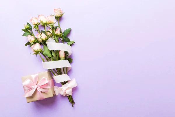 stock image design concept with pink rose flower and gift box on colored table background top view. Happy Holiday, Mothers day, birthday concept. Romantic flat lay composition.