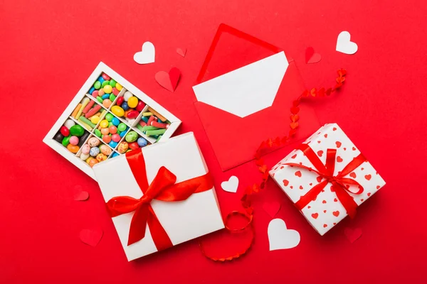 キャンディとギフトボックスとバレンタインの心を持つ赤い封筒の色を背景に フラットレイアウト トップビュー 休日の概念のためのロマンチックな愛の手紙 — ストック写真