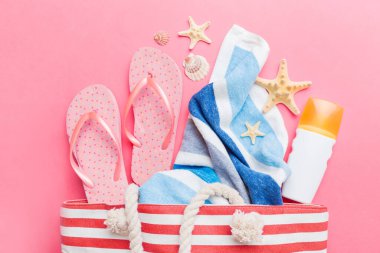 Plaj aksesuarları renkli arka plan yaz seyahati konseptinde düz bir görünüm sergiliyordu. İçinde deniz yıldızı ve deniz kabuğu olan bir çanta. Üst görünüm.