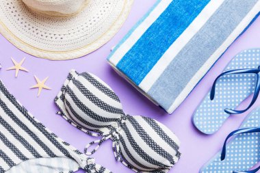 Kadın mayo ve plaj aksesuarları renkli arka plan yaz seyahati konseptine düz bir görünüm kazandırıyordu. Bikini mayo, hasır şapka ve deniz topuklu ayakkabı. Üst görünümü kopyala.