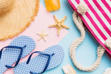 Beach accessories straw hat and seashell on colored table. Summer concept background.