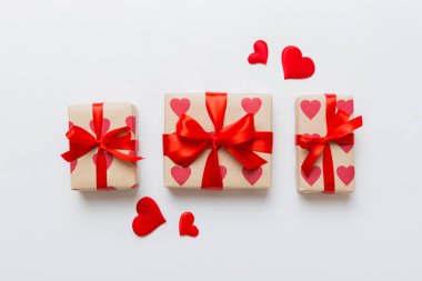 Top view photo of valentine day decorations gift box with red ribbon bow on colored background. Holiday gift boxes with top view.