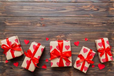 Top view photo of valentine day decorations gift box with red ribbon bow on colored background. Holiday gift boxes with top view.