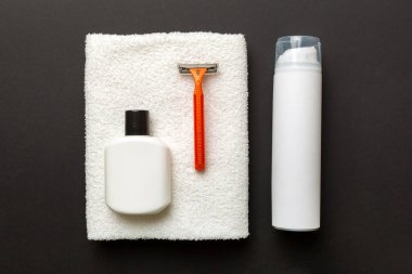 Tıraş Adam seti. Traş makinesi, havlu, losyon ve renkli arka planda tıraş köpüğü. Erkekler banyo aksesuarları üst görünüm.