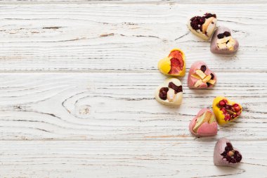 chocolate sweets in the form of a heart with fruits and nuts on a colored background. top view with space for text, holiday concept.