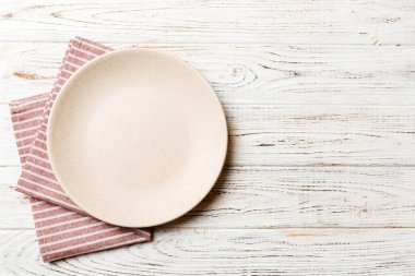 Renkli arka planda üst görünüm yiyecek için masa örtüsü üzerindeki boş yuvarlak beyaz tabak. Tasarımınız için boşluk olan peçeteye boş tabak.