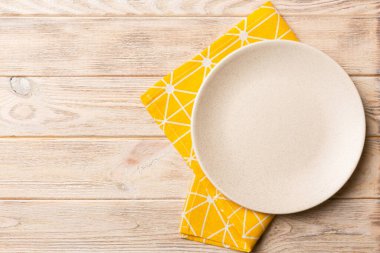 Renkli arka planda üst görünüm yiyecek için masa örtüsü üzerindeki boş yuvarlak beyaz tabak. Tasarımınız için boşluk olan peçeteye boş tabak.