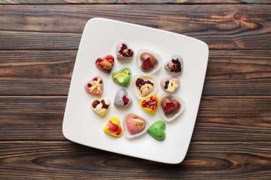 Plate with different chocolate on colored background. Assortment of fine chocolates top view vith copy space Health and obesity concept.
