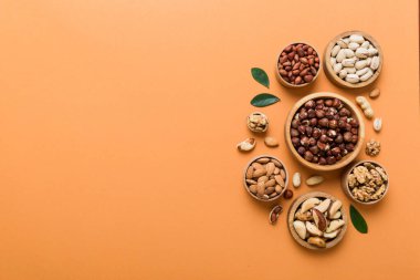 mixed nuts in wooden bowl. Mix of various nuts on colored background. pistachios, cashews, walnuts, hazelnuts, peanuts and brazil nuts.