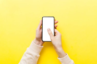 Mesajınız veya bilgi içeriğiniz için boş bir kopya ekranı olan akıllı telefonları tutan kadın ellerinin üst görünümü. üst görünümde telefon beyaz ekranı kullanan kadın eli.