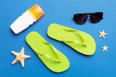 Yaz yolculuğu konsepti. Parmak arası terlikler, güneş gözlükleri ve beyaz üzerine deniz yıldızı. Renkli arkaplanda üst görünüm.