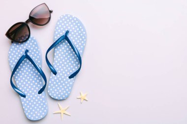 Yaz yolculuğu konsepti. Parmak arası terlikler, güneş gözlükleri ve beyaz üzerine deniz yıldızı. Renkli arkaplanda üst görünüm.