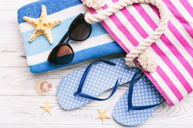 Plaj aksesuarları renkli arka plan yaz seyahati konseptinde düz bir görünüm sergiliyordu. İçinde deniz yıldızı ve deniz kabuğu olan bir çanta. Üst görünüm.