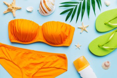 Kadın mayo ve plaj aksesuarları renkli arka plan yaz seyahati konseptine düz bir görünüm kazandırıyordu. Bikini mayo, hasır şapka ve deniz topuklu ayakkabı. Üst görünümü kopyala.