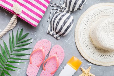 Kadın mayo ve plaj aksesuarları renkli arka plan yaz seyahati konseptine düz bir görünüm kazandırıyordu. Bikini mayo, hasır şapka ve deniz topuklu ayakkabı. Üst görünümü kopyala.
