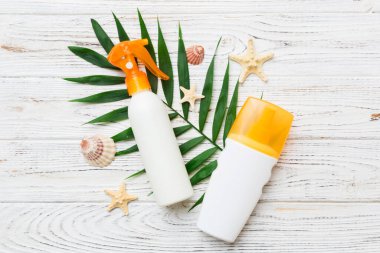 Güneş kremi şişesi. Güneş korumalı krem ve tropik yeşil yapraklı deniz kabukları olan bir şişe..