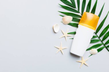 Güneş kremi şişesi. Güneş korumalı krem ve tropik yeşil yapraklı deniz kabukları olan bir şişe..