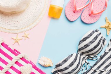 Kadın mayo ve plaj aksesuarları renkli arka plan yaz seyahati konseptine düz bir görünüm kazandırıyordu. Bikini mayo, hasır şapka ve deniz topuklu ayakkabı. Üst görünümü kopyala.