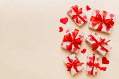 Top view photo of valentine day decorations gift box with red ribbon bow on colored background. Holiday gift boxes with top view.
