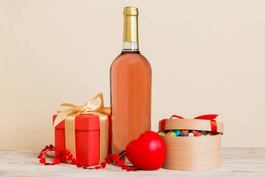 Bottle of wine on colored background for Valentine Day with gift box. Heart shaped with presrnt box perspective view with copy space.