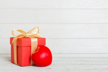 gift box with red bow and red heart on colored background. Perspective view. Flat lay.
