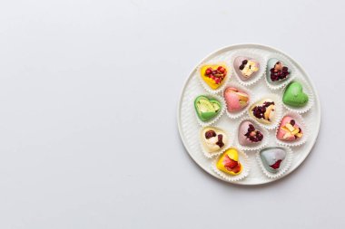 Plate with different chocolate on colored background. Assortment of fine chocolates top view vith copy space Health and obesity concept.