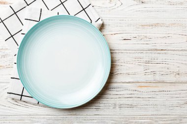 Renkli arkaplanda üst görünüm yiyecek için mavi tabak üzerinde boş. Tasarımınız için boşluk olan peçeteye boş tabak.