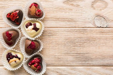 chocolate sweets in the form of a heart with fruits and nuts on a colored background. top view with space for text, holiday concept.