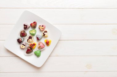 Plate with different chocolate on colored background. Assortment of fine chocolates top view vith copy space Health and obesity concept.
