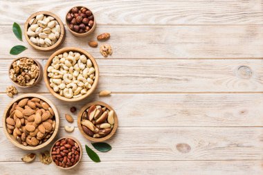 mixed nuts in wooden bowl. Mix of various nuts on colored background. pistachios, cashews, walnuts, hazelnuts, peanuts and brazil nuts.