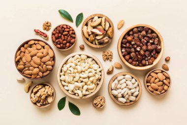 mixed nuts in wooden bowl. Mix of various nuts on colored background. pistachios, cashews, walnuts, hazelnuts, peanuts and brazil nuts.