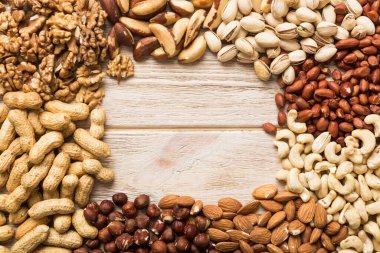 different nuts frame background. Close up, top view, flat lay with vopy space. Walnut, pistachios, almonds, hazelnuts and cashews.