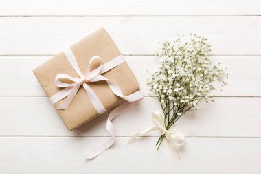 Hediye kutusu ya da hediye kutusu ve çiçek çıngıraklı yılanı ışık masasının üstünde. Tebrik kartı. Kopya alanı ile düz uzanma biçimi.