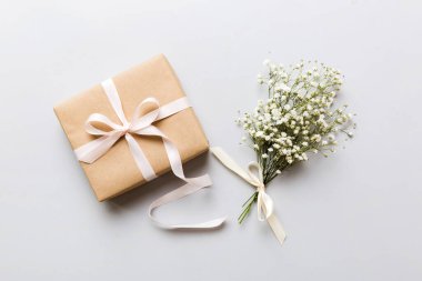 Hediye kutusu ya da hediye kutusu ve çiçek çıngıraklı yılanı ışık masasının üstünde. Tebrik kartı. Kopya alanı ile düz uzanma biçimi.