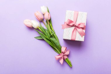 Pembe lale çiçekleri ve hediye ya da renkli masa arkaplanındaki hediye kutusu. Anneler günü, doğum günü, kadınlar günü, kutlama konsepti. Metin üstü görünümü için boşluk.