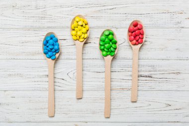 Renkli arka planda kaşık üzerinde renkli tatlı şekerler. Fotokopi alanı ile şekerleme dekoru üst görünümü.