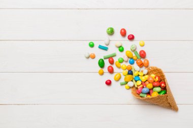 waffle cone full of assorted traditional candies falling out on colored background with copy space. Happy Holidays sale concept.