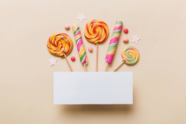 Tatil kompozisyonu yatıyordu. Kağıt boş, lolipop, renkli arka planda doğum günü süslemeleri. Üst görünüm, metin için boşluk kopyala.