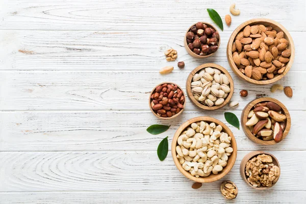 Stock image mixed nuts in wooden bowl. Mix of various nuts on colored background. pistachios, cashews, walnuts, hazelnuts, peanuts and brazil nuts.