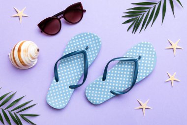 Yaz yolculuğu konsepti. Parmak arası terlikler, güneş gözlükleri ve beyaz üzerine deniz yıldızı. Renkli arkaplanda üst görünüm.