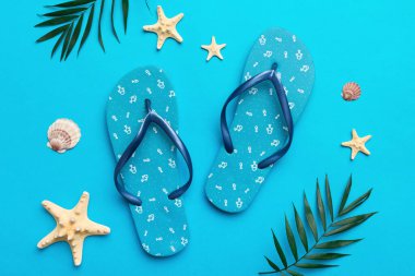 Renkli arka planda parmak arası terlikleri ve deniz kabuğu olan düz bir kompozisyon. Metin üstü görünümü için boşluk.