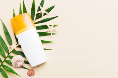 Güneş kremi şişesi. Güneş korumalı krem ve tropik yeşil yapraklı deniz kabukları olan bir şişe..