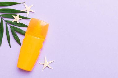 Güneş kremi şişesi. Güneş korumalı krem ve tropik yeşil yapraklı deniz kabukları olan bir şişe..